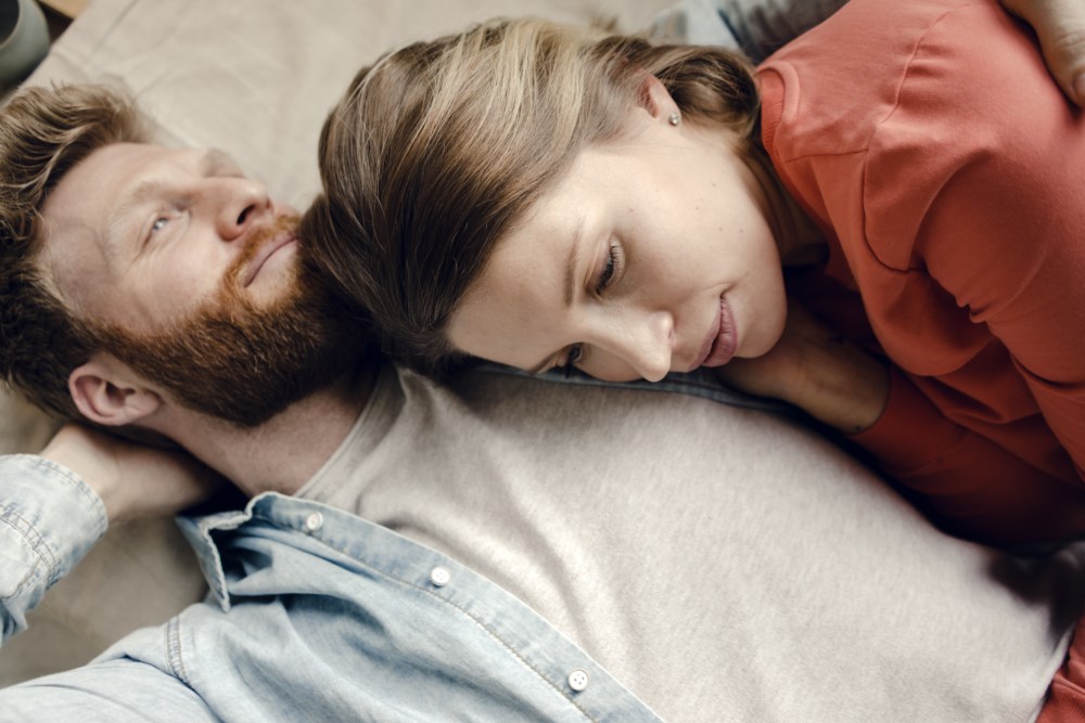 Tankefullt par som ligger på en seng